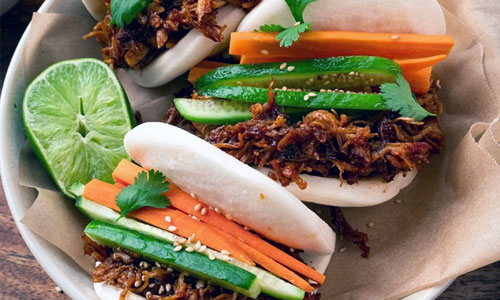 Three freshly steamed Bao Buns filled with savory tofu and pickled greens.